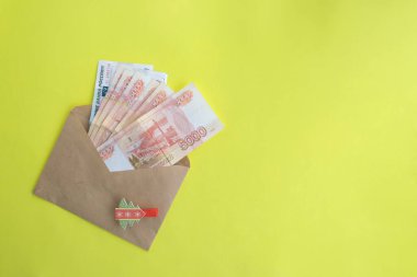 Sarı arka planda, içinde para olan bir zarf, beş bin ruble Rus parası. Ekonomi konsepti, para dağılımı. Yeni yıl hediyesi..