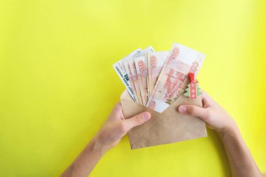 Sarı arka planda, içinde para olan bir zarf, beş bin ruble Rus parası. Ekonomi konsepti, para dağılımı. Yeni yıl hediyesi..