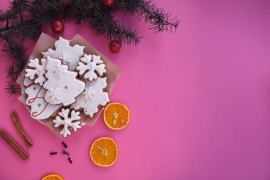 Pembe arka planda, Noel kurabiyesi, portakal, tarçın ve bir Noel ağacı dalı. Metin için boş alanı olan kompozisyon. Üst manzara, düz uzanma.