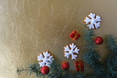 Kar taneleri şeklinde Noel kurabiyeleri, bir Noel ağacı dalı ve altın arka planda yeni yıl süslemeleri. Metin için yer.