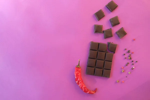 Tvůrčí maketa z čokolády, červená paprika na růžovém pozadí. — Stock fotografie
