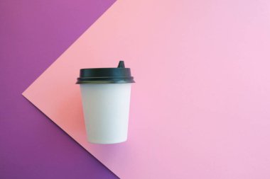 Menekşe pembesi arka planda tek kullanımlık bir bardak.