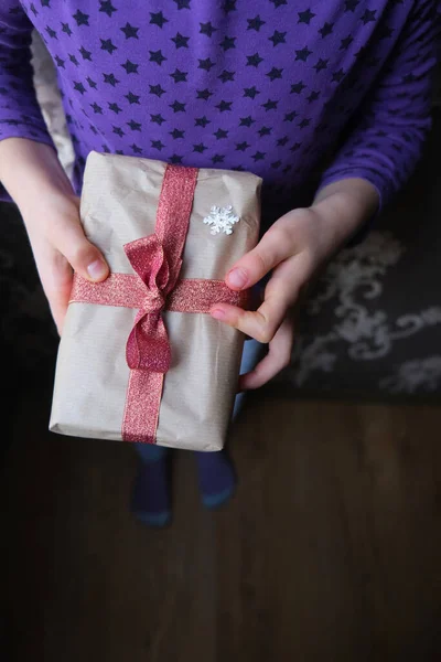 Les mains tiennent un cadeau enveloppé dans du papier et un ruban rouge à l'intérieur. — Photo