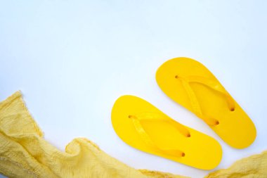 Afiş arka planı. Sarı parmak arası terlikler ve beyaz arka planda bir havlu..