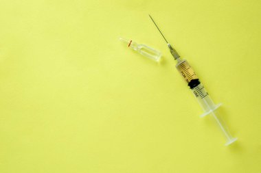 Sarı arka planda aşılı şırınga. COVID-19.