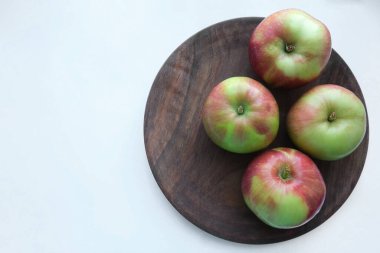 Red apples on a wooden plate against white background. Apples as a background. Flat lay, top view, copy space