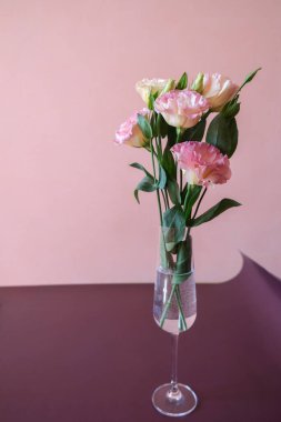 Vazoda pembe Eustoma çiçekleri ya da mor bir masada cam..