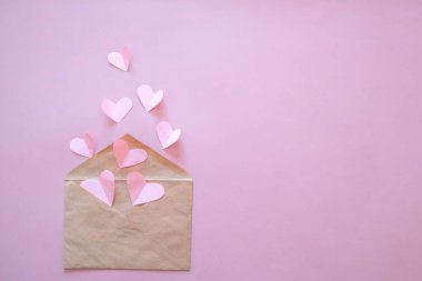 Yaratıcı minimum Sevgililer Günü konsepti. Zarf, sevgililer günü kartı, pastel pembe arka planda beyaz ve pembe kalp konfetisi. Düz konum, üst görünüm, kopyalama alanı