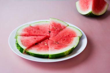 Pembe arka planda büyük kırmızı çiğ karpuz dilimleri, uzay manzarasını kopyala. Et tatlıdır, suludur, genellikle koyu kırmızıdan pembeye.