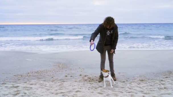年轻男子和他上海滩慢动作的狗玩 — 图库视频影像