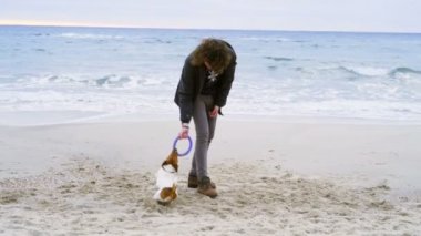 genç adam onun köpek plaj yavaş hareket üstünde yüzük oyuncak atmak