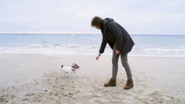 Jonge man spelen met zijn hond op het strand slow motion — Stockvideo