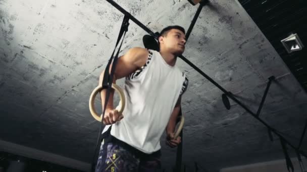 Joven macho haciendo ring dips en el gimnasio cámara lenta — Vídeos de Stock