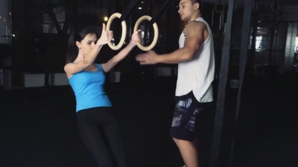 Young female fitness novice gets ready for ring row with male trainer — Stock Video