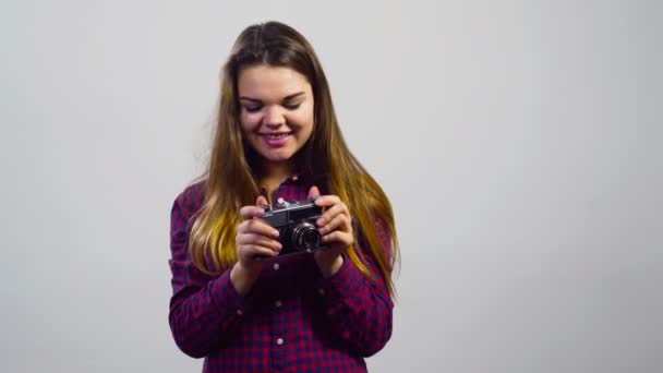 Молодая девушка использует старую кинокамеру перед белым фоном — стоковое видео
