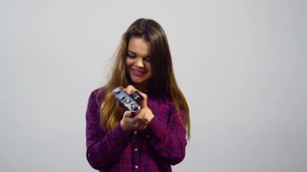 Joven chica hace selfie con la vieja cámara de cine delante de fondo blanco — Vídeos de Stock