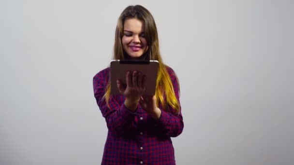 Ung flicka erbjuda elektroniska varor i tablet PC framför vita vägg — Stockvideo