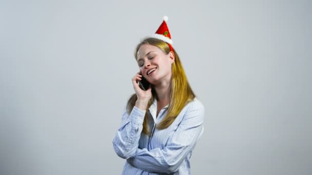 快乐的年轻女孩，戴着圣诞帽通电话 — 图库视频影像