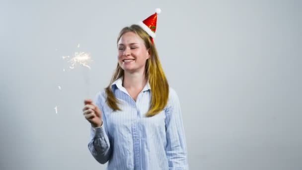 Feliz chica joven con sombrero de Navidad y la celebración de un brillo — Vídeo de stock