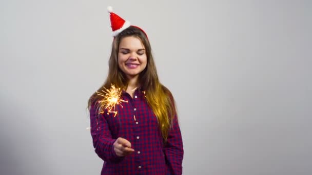 Beyaz duvar önünde Noel şapka ve maytap mutlu duygu ile genç kız — Stok video