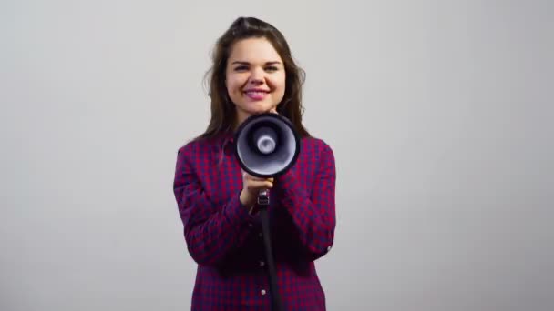 Young girl use megaphone to camera in front of white wall — Stock Video