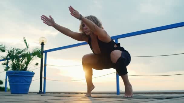 Молода жінка практикує йогу на терасі біля моря — стокове відео