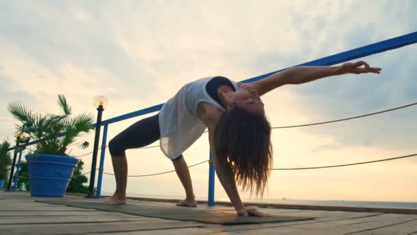 Young female practicing yoga on the terrace by the sea — Stock Video