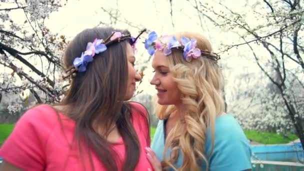 Due ragazze che si baciano nel parco dei fiori primaverili slow motion — Video Stock