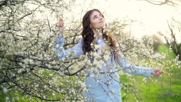 Ung kvinna poserar under blommande träd slow motion — Stockvideo