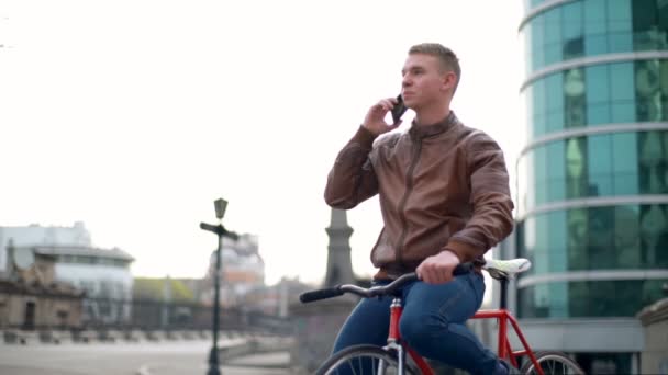 ダウンタウンのスローモーションで電話で若い男性自転車協議 — ストック動画