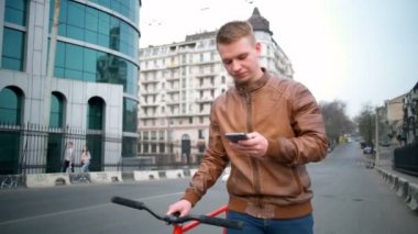 Bisiklet sokak ağır çekimde yakınındaki bir smartphone erkek bisikletçi kullanarak yürüyor