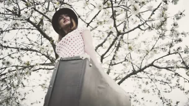 Mujer joven vestida en estilo retro posando en floreciente jardín cámara lenta — Vídeos de Stock