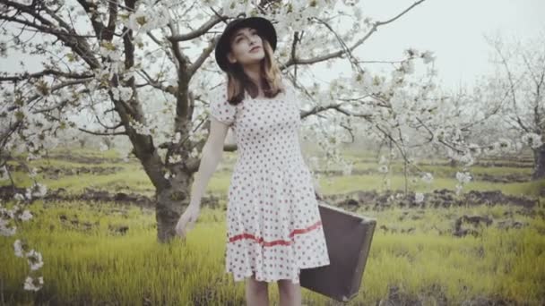 Mujer joven vestida en estilo retro posando en floreciente jardín cámara lenta — Vídeos de Stock