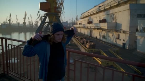 Ung man innehar en skateboard promenader längs havet hamnen i gryningen ultrarapid — Stockvideo