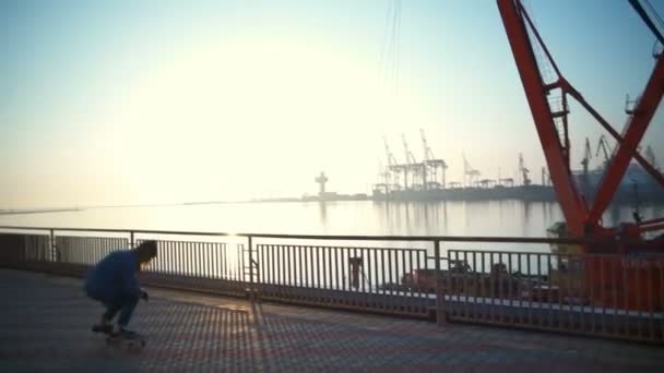 Jovem skate no porto marítimo ao amanhecer câmera lenta — Vídeo de Stock