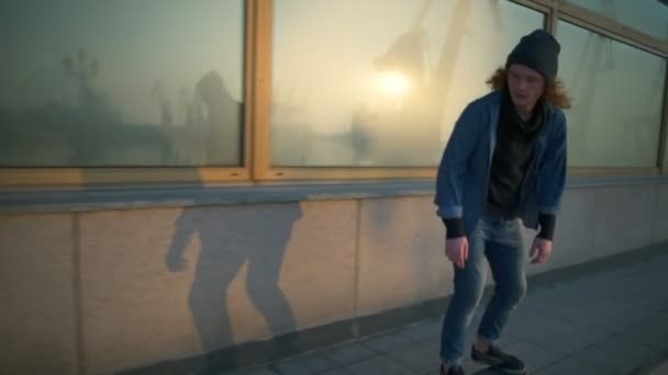 Молодой человек катается на скейтборде в морском порту на рассвете — стоковое видео