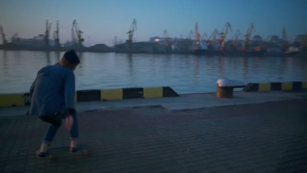 Jongeman skateboarden in de zeehaven op dageraad slow motion — Stockvideo