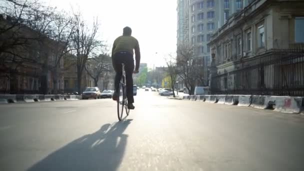 Bakifrån man rider en cykel på tomma gatan i sol ljus slow motion — Stockvideo