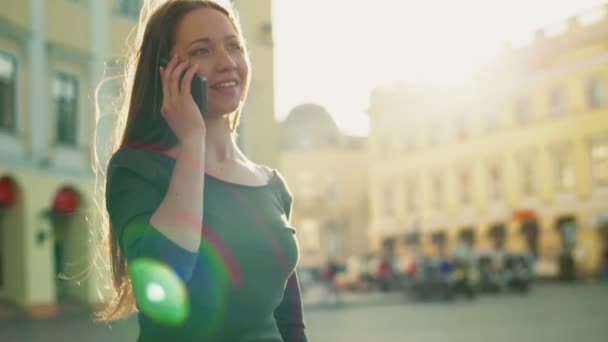 Счастливая женщина разговаривает по телефону в центре города — стоковое видео