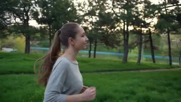 Joven mujer corre en parque cámara lenta — Vídeo de stock