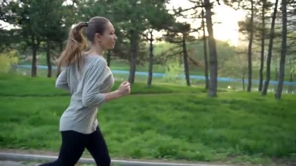 Joven mujer corre en parque cámara lenta — Vídeo de stock