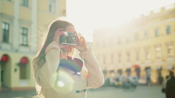 Молодая женщина фотографирует город со старой камерой замедленной съемки — стоковое видео