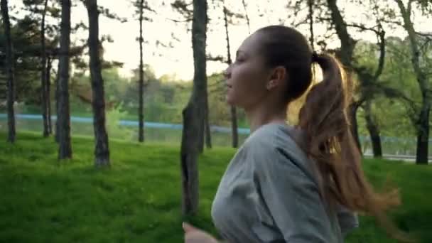 Молодая женщина бегает в парке замедленной съемки — стоковое видео