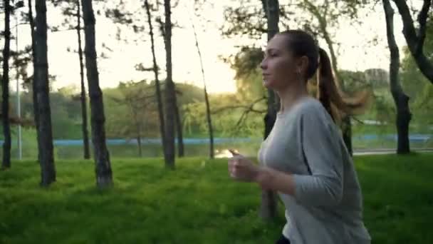 Joven mujer corre en parque cámara lenta — Vídeo de stock