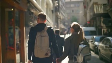 birbirlerinin ellerini yavaş tutan sokakta yürüyen Çift