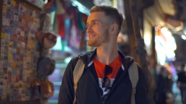 Férfi turisztikai körülnézett az esti piacon lassú mozgás — Stock videók