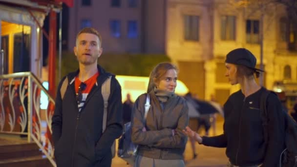 Twee meisjes en een jongen die wandelen in de avond stad slow motion — Stockvideo