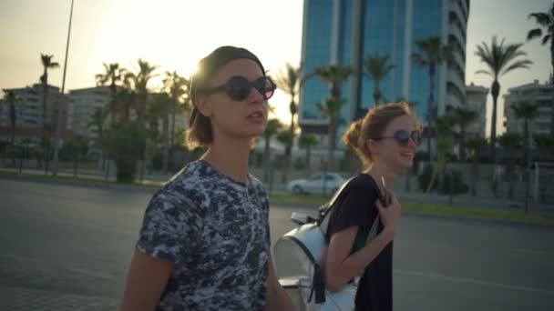 Duas meninas usando óculos de sol indo na calçada câmera lenta — Vídeo de Stock