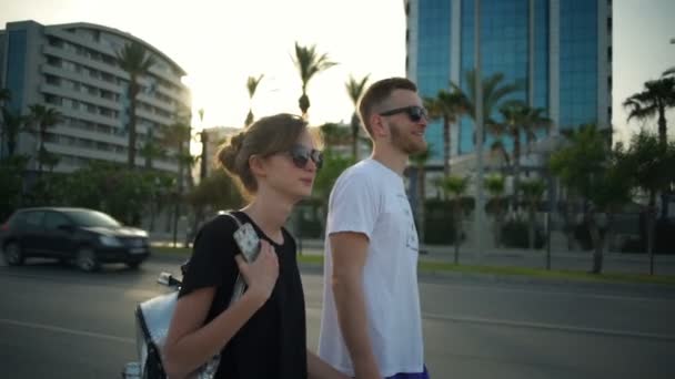 Jeune couple portant des lunettes de soleil le long de la route au ralenti — Video