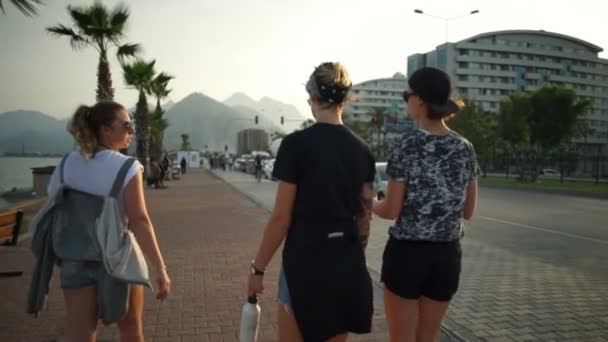 Вид ззаду трьох дівчат, що йдуть у курортному місті повільний рух — стокове відео